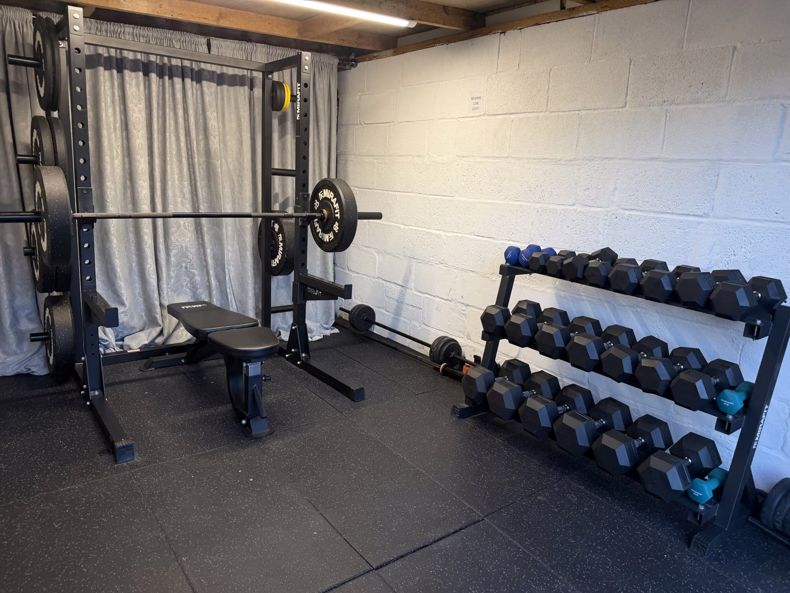 Private home gym with squat rack, weight bench and barbell